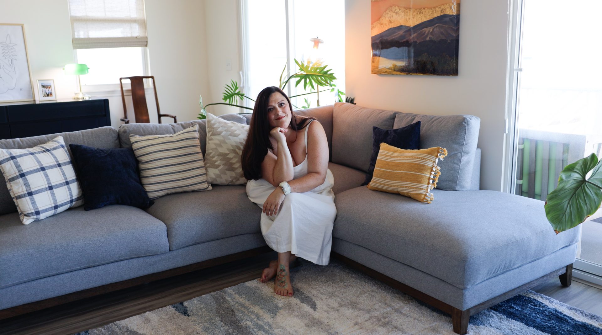Melissa Whittington sitting on a gray sofa in a bright, inviting living room.